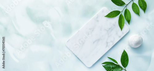Top view of empty marble podium and green leaves on light blue background . Pedestal and fresh natural leaf for cosmetic advertising. Eco product presentation mockup. flat lay.