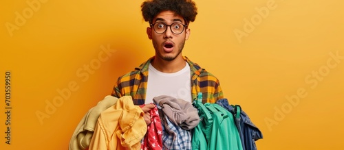 A skeptical, sarcastic young man holds laundry items, looking shocked and surprised. photo