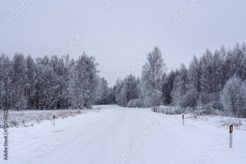 Fototapeta Naklejka Na Ścianę i Meble -  frost-covered electricity wires crossing a road in the countryside - a winter landscape