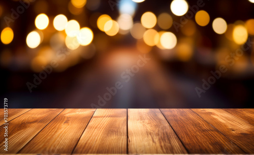 The wooden table sits bare, surrounded by blurred lights in the background.