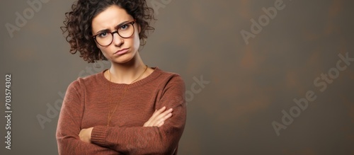 Middle-aged Latin woman in casual clothes and glasses, showing skepticism and nervousness, disapprovingly crosses her arms with a negative expression. photo