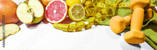 Lose weight with healthy eating, fitness and control, symbolized by fresh fruits, dumbbells and a measuring tape on a light gray background, wide panoramic format, copy space photo