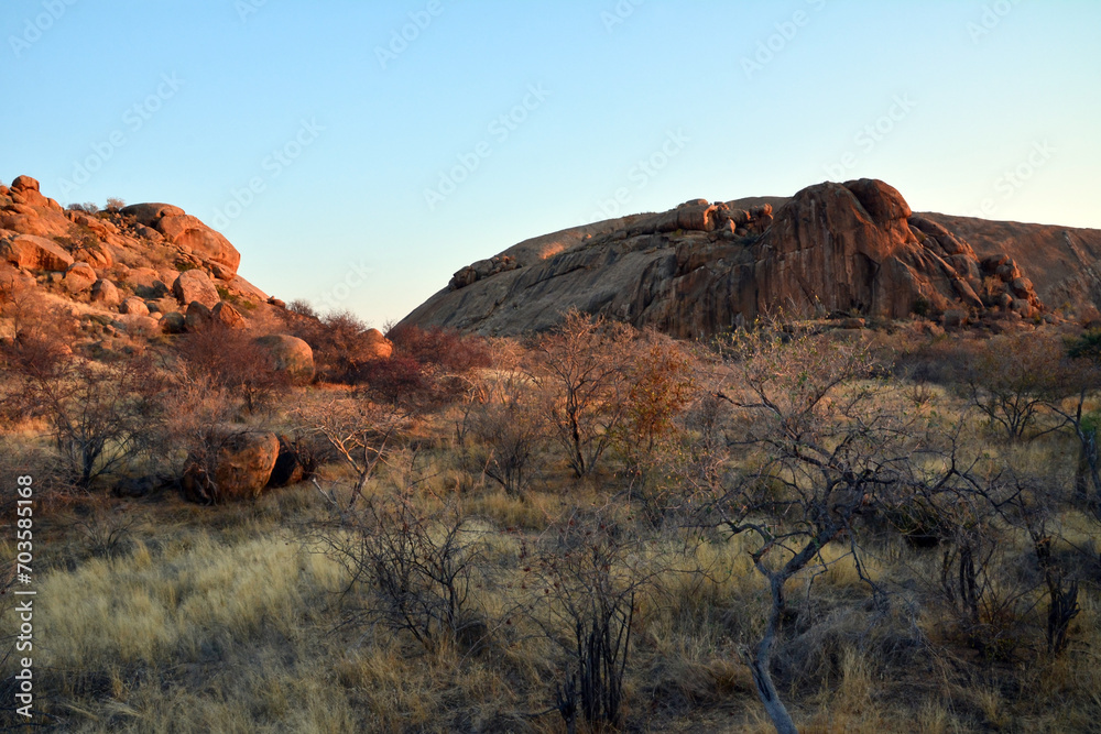 Large boulders are scattered along the rocky mountain slope. Blue sky above Large boulders are scattered along the rocky mountain slope. Blue sky above
