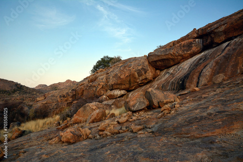 Large boulders are scattered along the rocky mountain slope. Blue sky above