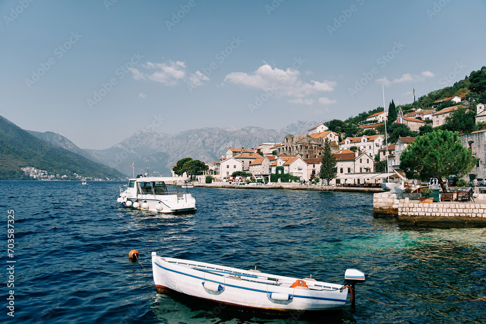 White fishing boat is moored at a pier near the shore of Perast. Montenegro