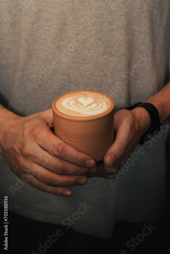 close up of hands holding cup of coffee with milk design