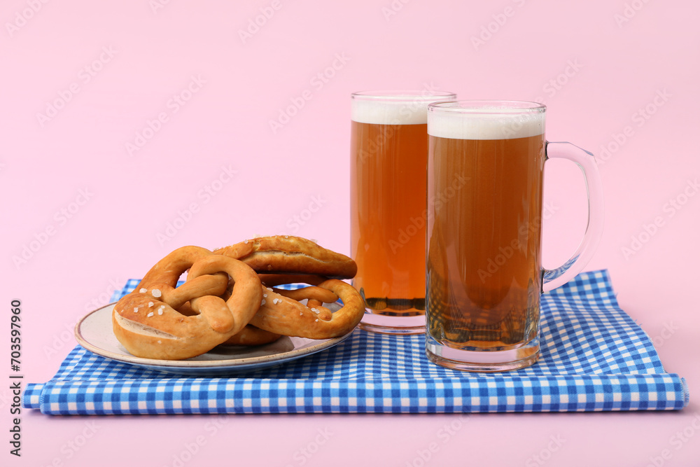 Mugs of cold beer and plate with tasty pretzels on pink background. Oktoberfest celebration Mugs of cold beer and plate with tasty pretzels on pink background. Oktoberfest celebration