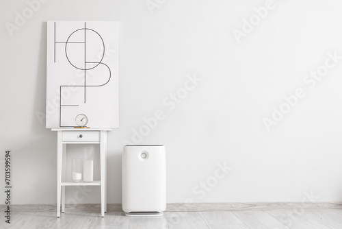 Air purifier and table with decor near light wall in room © Pixel-Shot