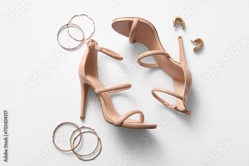Pair of stylish high-heeled shoes, bracelets and earrings on white background