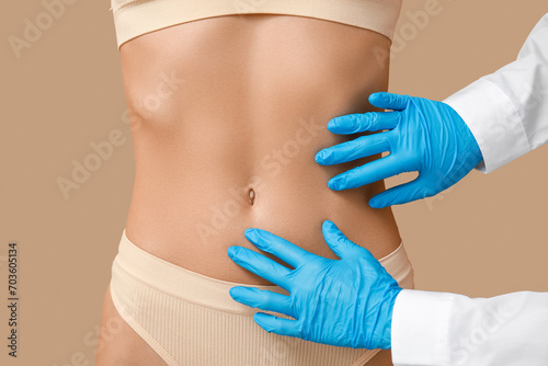Young woman with flat belly and plastic surgeon on beige background, closeup © Pixel-Shot