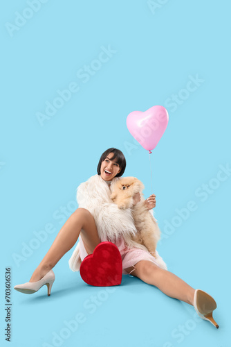Beautiful young woman with heart-shaped air balloon and gift for Valentine's day on blue background © Pixel-Shot