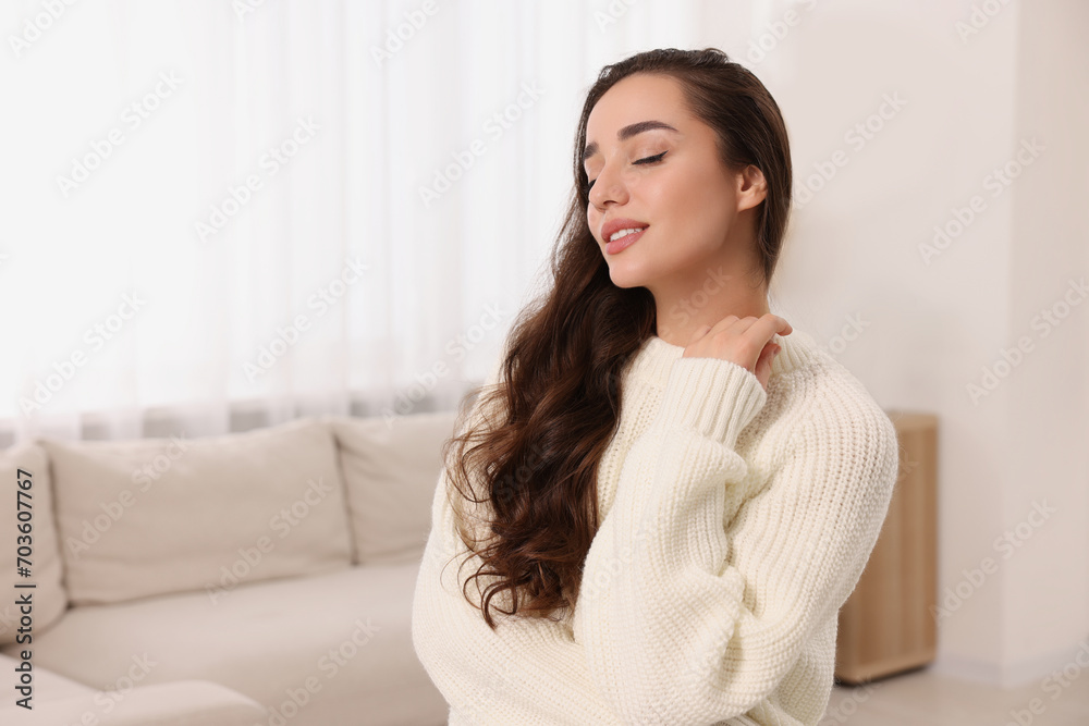 Beautiful young woman in stylish warm sweater at home, space for text Beautiful young woman in stylish warm sweater at home, space for text