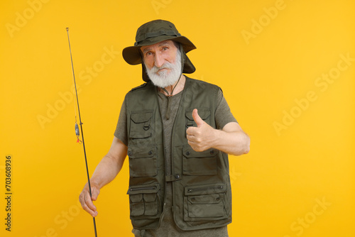 Fisherman with fishing rod showing thumb up on yellow background