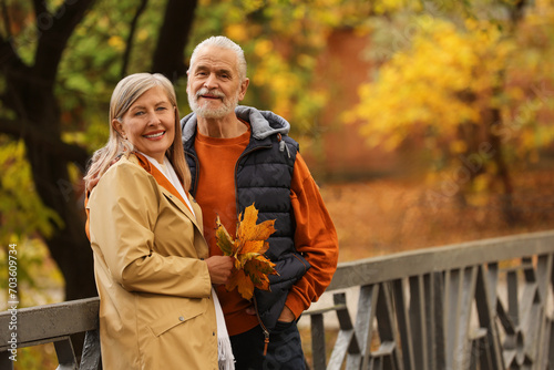 Bild auf Leinwand Affectionate senior couple with dry leaves in autumn park, space for text