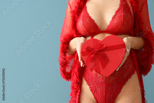 Sexy young woman in lingerie with gift box on blue background, closeup. Valentine's Day celebration © Pixel-Shot
