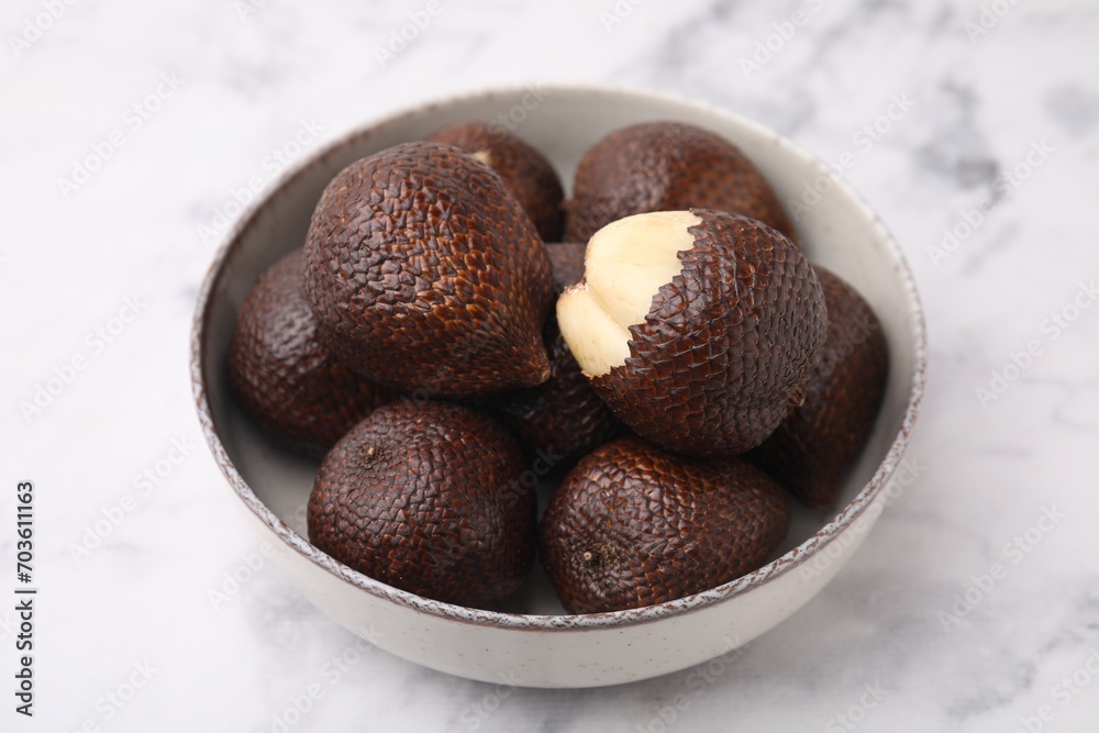 Fresh salak fruits in bowl on white marble table, closeup