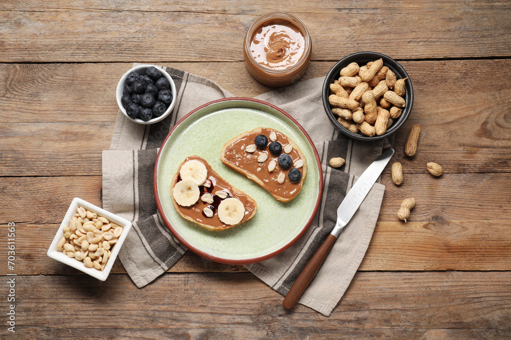 Toasts with tasty nut butter, banana slices, blueberries and peanuts on wooden table, flat lay Toasts with tasty nut butter, banana slices, blueberries and peanuts on wooden table, flat lay