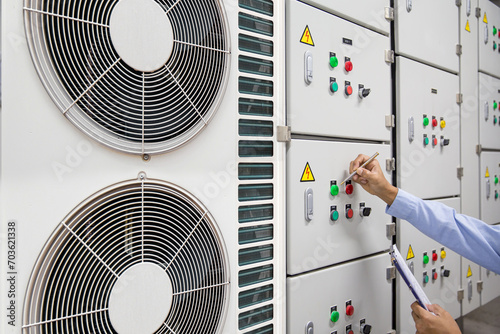 Foto Electrical engineer checking electric at circuit breaker of air handling unit (AHU) starter control panel for air conditioner or load center cabinet for maintenance in main power distribution room