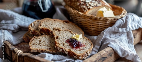 Homemade rye and wheat bread with cherry jam and butter on a wooden pan, wrapped in a towel. photo