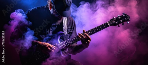 musician playing guitar with purple flare. dark background