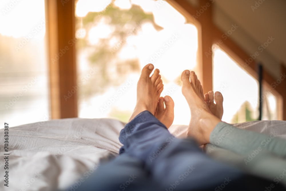 Couples feet relaxing in bed early morning, people love and relationships concept - obrazy, fototapety, plakaty 