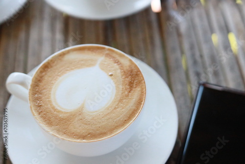 Hot latte in a white glass on a bamboo table