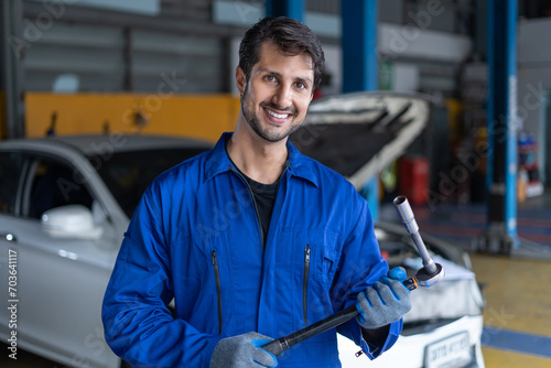Portrait of latin auto mechanic man holding wrench standing in garage cars service . hispanic technician repairing vehicle at garage . maintenance car repair service
