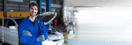 Portrait of latin auto mechanic man holding wrench standing in garage cars service . hispanic technician repairing vehicle at garage . maintenance car repair service . banner and copy space