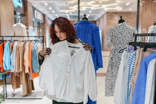 Shopping woman, women's fashion clothes in a store, boutique. Woman choosing clothes in a store