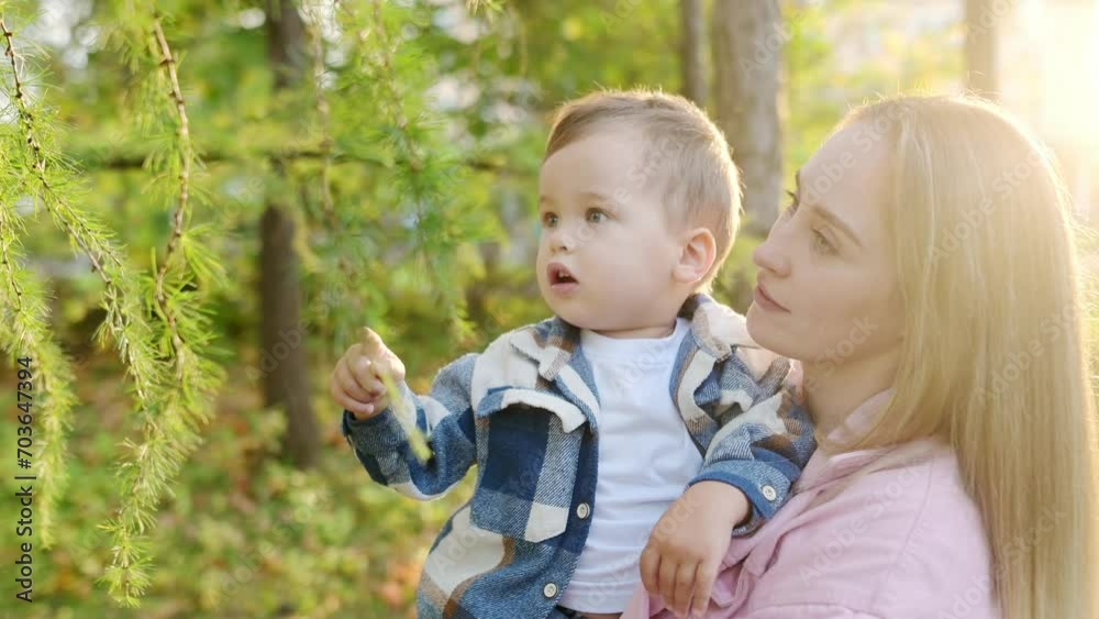 Young mother and little baby boy are watching for a snail during walk on sunny summer park. Mom and cute son are exploring nature. Quality family time. Young mother and little baby boy are watching for a snail during walk on sunny summer park. Mom and cute son are exploring nature. Quality family time.