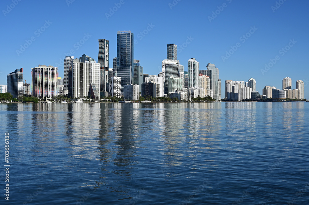 City of Miami, Florida skyline reflected in calm water of Biscayne Bay on calm cloudless December morning.