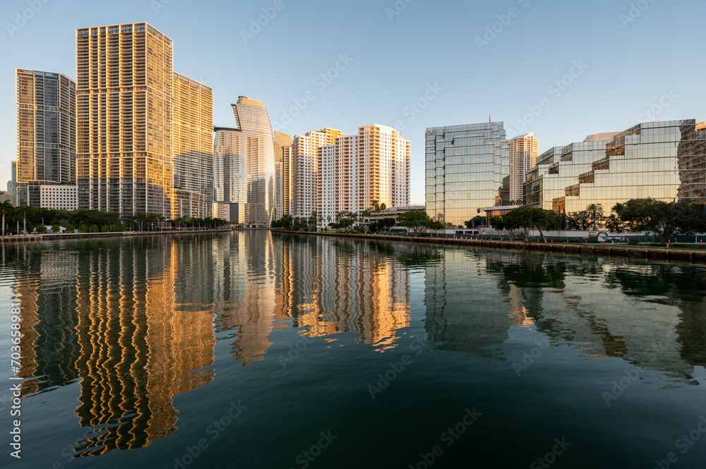 City of Miami, Florida skyline reflected in calm water of Biscayne Bay at sunrise on clear cloudless December morning.