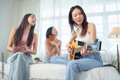 Asian women playing acoustic guitar and singing photo