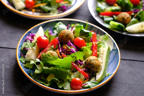 Salad de Falafel, consisting of lettuce, cucumber, scallions, cherry tomatoes, olives, sun-dried tomatoes, and feta. Falafel is a deep-fried ball or patty-shaped fritter made from ground chickpeas. 