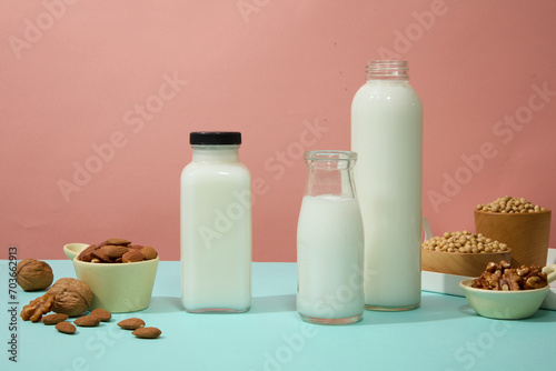 Photography Three milk bottles without label decorated with bowls of soybeans, almond and walnuts