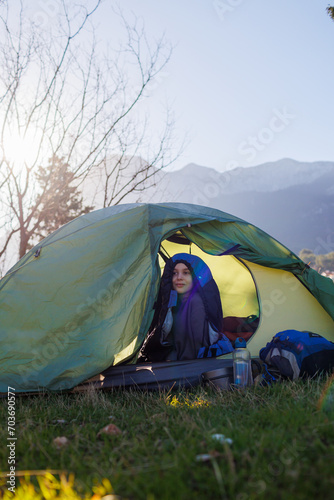 happy smiling child sitting in a tent against the backdrop of the mountains. baby in a sleeping bag. portrait of a child in a tent. camping and trekking with children.