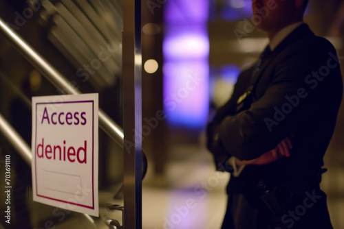 Access denied concept image with a door blocked by a security guard and sign to notify the denied access to the indoor part