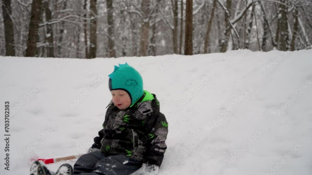 A joyful, carefree child slides down an ice slide in a winter forest during a family weekend. Little boy in warm winter clothes enjoys active lifestyle, family walk in winter forest on weekend. A joyful, carefree child slides down an ice slide in a winter forest during a family weekend. Little boy in warm winter clothes enjoys active lifestyle, family walk in winter forest on weekend.