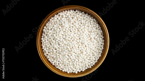 A video of Raw Sabudana (Tapioca Sago) in round Bowl on Black Background. photo