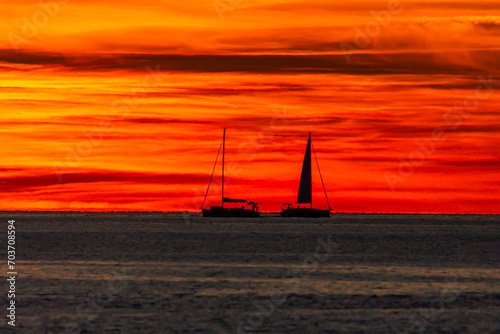 Sailboat passing in front of the sun at sunset from Fethiye Calis beach 
