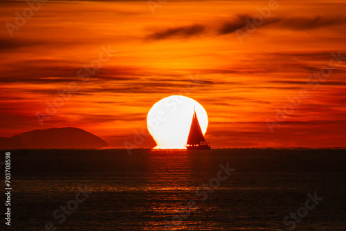 Sailboat passing in front of the sun at sunset from Fethiye Calis beach 