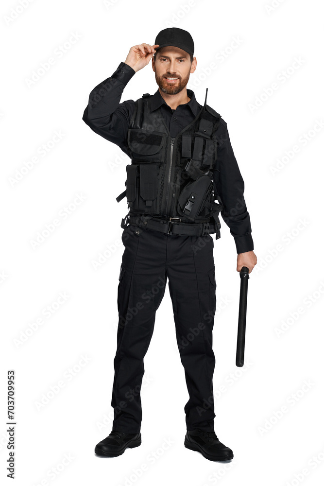 Smiling caucasian police officer in uniform standing with baton indoors. Front view of bearded cop with truncheon adjusting police cap, isolated on white studio background. Concept of work, outfit. Smiling caucasian police officer in uniform standing with baton indoors. Front view of bearded cop with truncheon adjusting police cap, isolated on white studio background. Concept of work, outfit.