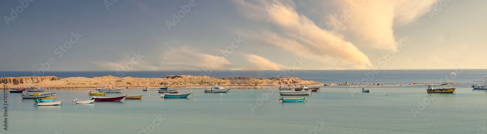 Alexandria, one of Egypt's oldest and most vibrant cities: Flotilla of weathered fishing boats bob gently on the waves, their colorful hulls contrasting with the dramatic clouds overhead