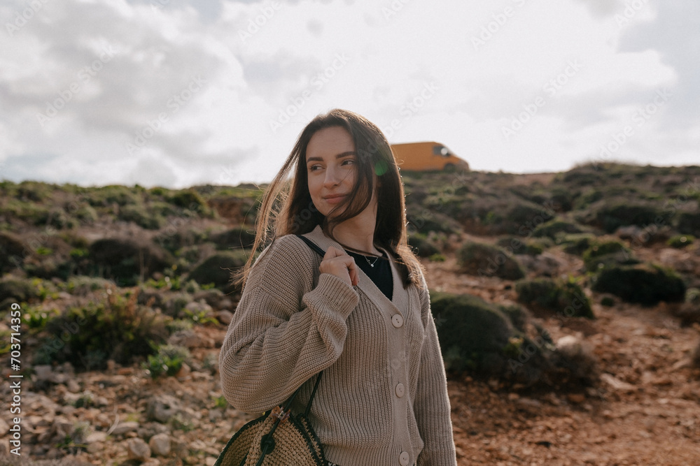Naklejka premium Beautiful caucasian woman traveling with backpack in mountains. Brown hair female wears beige sweater spend time outdoor. Concept weekend, lifestyle.