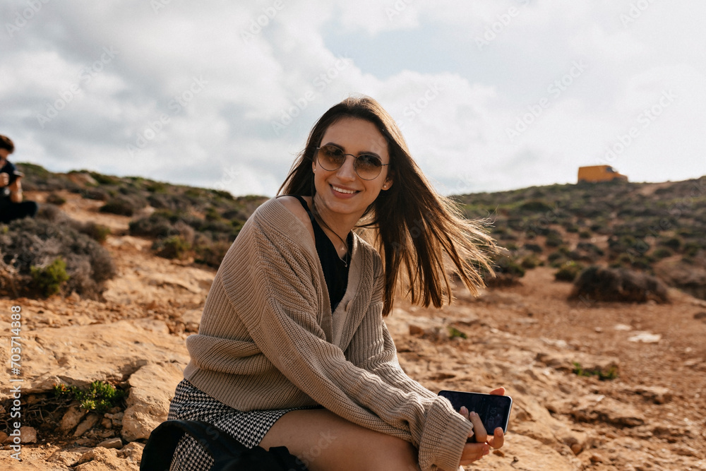 Smiling happy woman with loose hair and wonderful smile poison to camera against blue sky and mountains Smiling happy woman with loose hair and wonderful smile poison to camera against blue sky and mountains