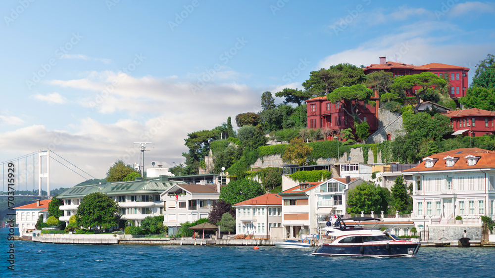 View from Bosphorus strait of the green mountains of the Asian side, with traditional houses and dense trees with Bosphorus Bridge in the far end in a summer day, Istanbul, Turkey