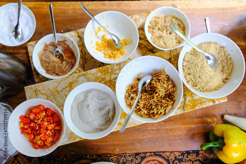 Top view of many type of condiments and topping served on top of the table with batik pattern as background. Indonesian Food served in restaurant, hotel, travel and culinary concept.