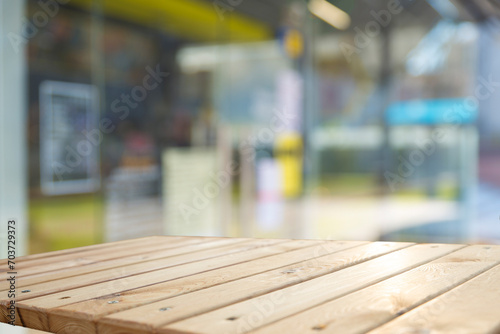 Wood table top on blur glass window wall building background.For montage product display or design key visual layout background. High quality photo