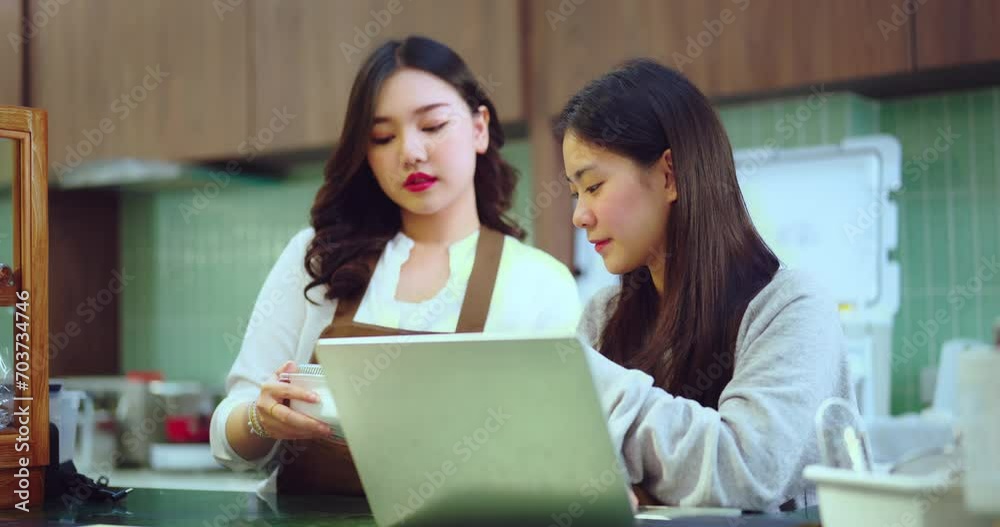 Beautiful young Asian woman working at the bar counter at a coffee shop or restaurant. Together they use computers to promote their own businesses. Beautiful young Asian woman working at the bar counter at a coffee shop or restaurant. Together they use computers to promote their own businesses.