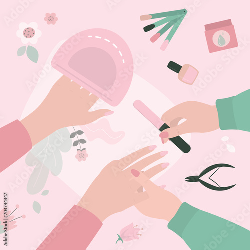 Manicurist uses nailfile and nail polish for manicure procedure. Caucasian woman at manicure salon. Beauty salon, manicure tools on table. Nails and beauty. Gel laque. Gel polish.